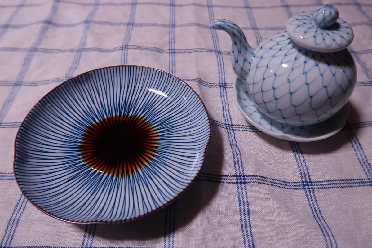 醤油差しから白い小皿(手塩皿)へ細く注がれる濃い褐色の濃口醤油